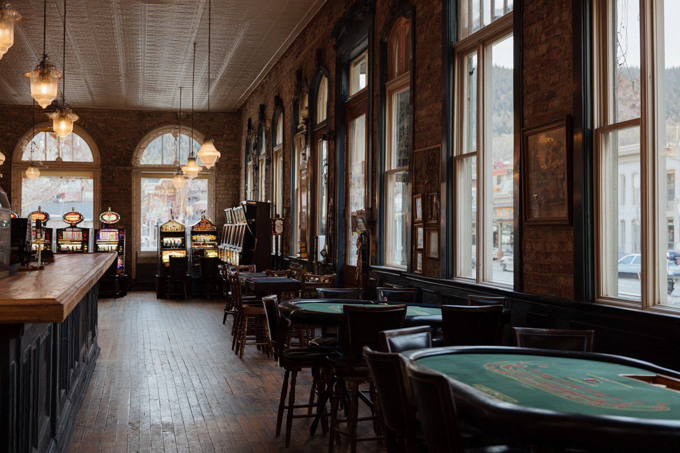 Historic Deadwood casino interior with brick walls, card tables and classic slot machines