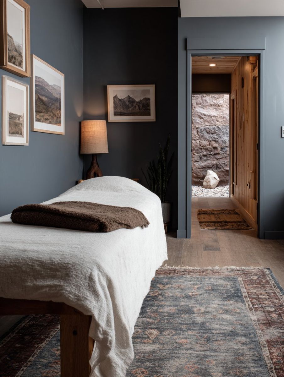 Massage room with slate blue walls, landscape prints and a cedar sauna doorway