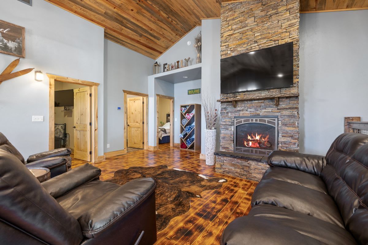 Great room with stone fireplace and leather sofas at Whiskey Barrel Lodge, a Deadwood Connections vacation rental