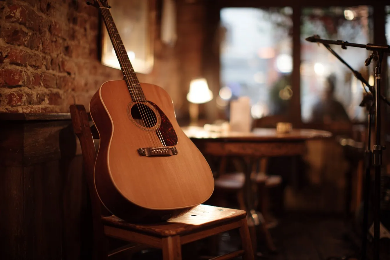Acoustic guitar resting on a wooden chair beside a microphone stand in a warmly lit historic saloon